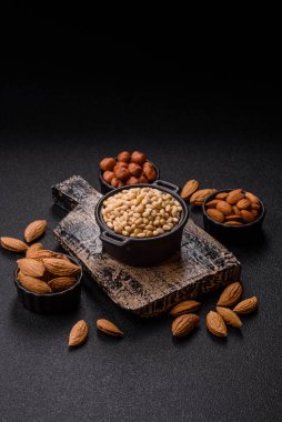 Koyu beton arka planda bir kasede soyulmuş çam fıstığı. Protein kaynağı olarak fındık.