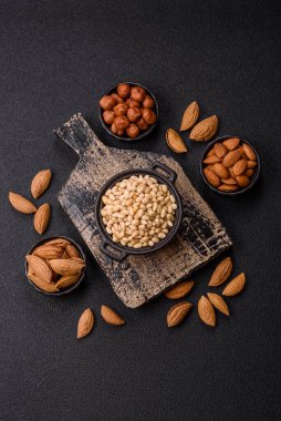 Koyu beton arka planda bir kasede soyulmuş çam fıstığı. Protein kaynağı olarak fındık.