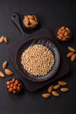 Koyu beton arka planda bir kasede soyulmuş çam fıstığı. Protein kaynağı olarak fındık.