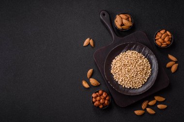 Koyu beton arka planda bir kasede soyulmuş çam fıstığı. Protein kaynağı olarak fındık.