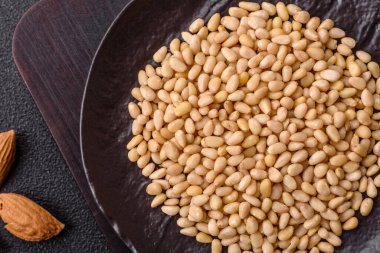 Koyu beton arka planda bir kasede soyulmuş çam fıstığı. Protein kaynağı olarak fındık.