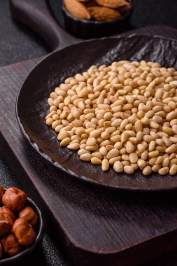 Koyu beton arka planda bir kasede soyulmuş çam fıstığı. Protein kaynağı olarak fındık.