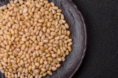 Koyu beton arka planda bir kasede soyulmuş çam fıstığı. Protein kaynağı olarak fındık.