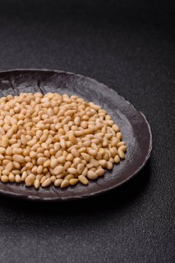 Koyu beton arka planda bir kasede soyulmuş çam fıstığı. Protein kaynağı olarak fındık.