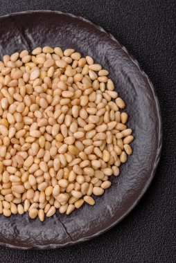 Koyu beton arka planda bir kasede soyulmuş çam fıstığı. Protein kaynağı olarak fındık.