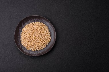 Koyu beton arka planda bir kasede soyulmuş çam fıstığı. Protein kaynağı olarak fındık.