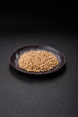 Koyu beton arka planda bir kasede soyulmuş çam fıstığı. Protein kaynağı olarak fındık.