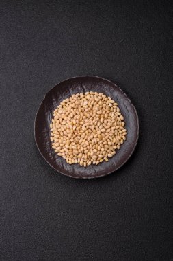 Koyu beton arka planda bir kasede soyulmuş çam fıstığı. Protein kaynağı olarak fındık.