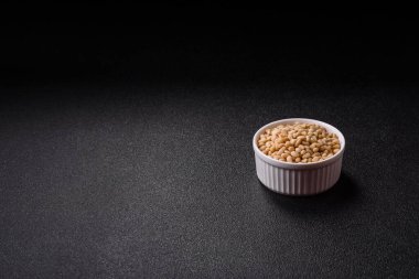 Koyu beton arka planda bir kasede soyulmuş çam fıstığı. Protein kaynağı olarak fındık.