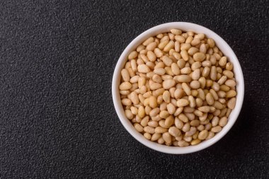 Koyu beton arka planda bir kasede soyulmuş çam fıstığı. Protein kaynağı olarak fındık.