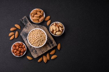 Koyu beton arka planda bir kasede soyulmuş çam fıstığı. Protein kaynağı olarak fındık.