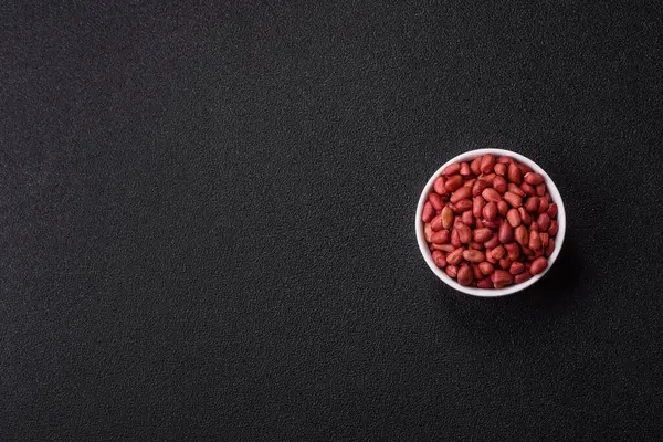 Koyu beton arka planda bir kasede yer fıstığı ya da kabuğu soyulmuş graundnut. Protein kaynağı olarak fındık
