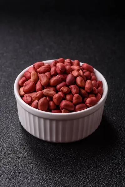 Koyu beton arka planda bir kasede yer fıstığı ya da kabuğu soyulmuş graundnut. Protein kaynağı olarak fındık