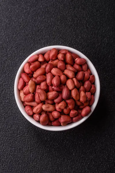 Koyu beton arka planda bir kasede yer fıstığı ya da kabuğu soyulmuş graundnut. Protein kaynağı olarak fındık