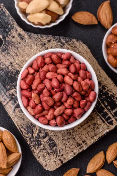 Koyu beton arka planda bir kasede yer fıstığı ya da kabuğu soyulmuş graundnut. Protein kaynağı olarak fındık