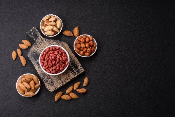 Koyu beton arka planda bir kasede yer fıstığı ya da kabuğu soyulmuş graundnut. Protein kaynağı olarak fındık