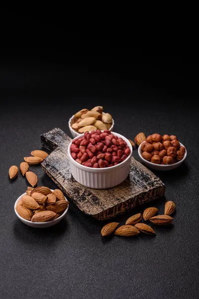 Koyu beton arka planda bir kasede yer fıstığı ya da kabuğu soyulmuş graundnut. Protein kaynağı olarak fındık