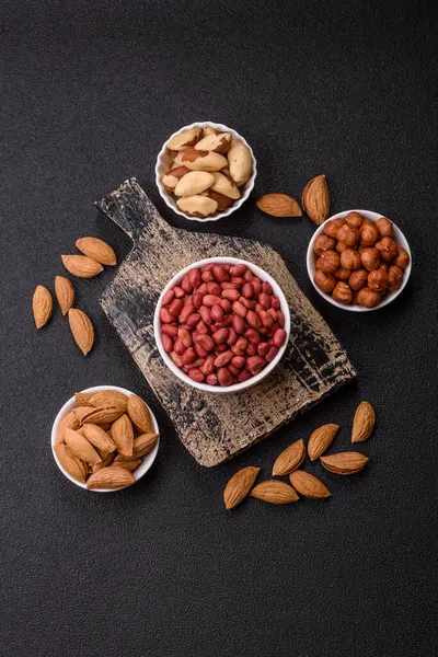 Koyu beton arka planda bir kasede yer fıstığı ya da kabuğu soyulmuş graundnut. Protein kaynağı olarak fındık