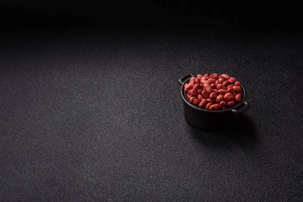 Koyu beton arka planda bir kasede yer fıstığı ya da kabuğu soyulmuş graundnut. Protein kaynağı olarak fındık
