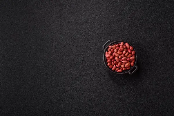 Koyu beton arka planda bir kasede yer fıstığı ya da kabuğu soyulmuş graundnut. Protein kaynağı olarak fındık