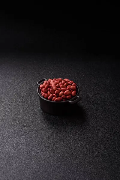 Koyu beton arka planda bir kasede yer fıstığı ya da kabuğu soyulmuş graundnut. Protein kaynağı olarak fındık