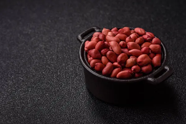 Koyu beton arka planda bir kasede yer fıstığı ya da kabuğu soyulmuş graundnut. Protein kaynağı olarak fındık