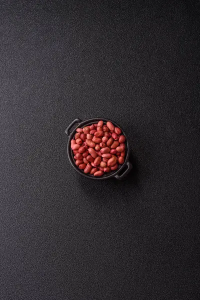 Koyu beton arka planda bir kasede yer fıstığı ya da kabuğu soyulmuş graundnut. Protein kaynağı olarak fındık