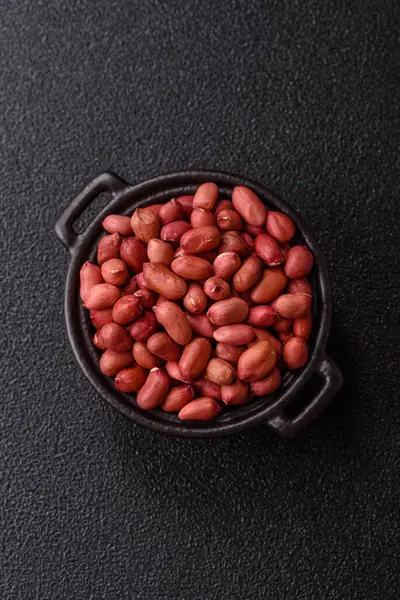 Koyu beton arka planda bir kasede yer fıstığı ya da kabuğu soyulmuş graundnut. Protein kaynağı olarak fındık