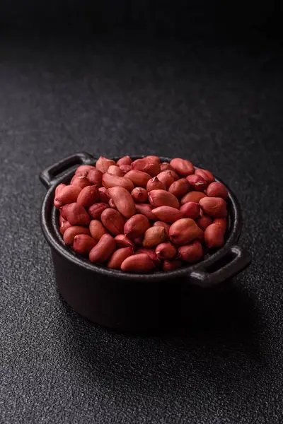 Koyu beton arka planda bir kasede yer fıstığı ya da kabuğu soyulmuş graundnut. Protein kaynağı olarak fındık