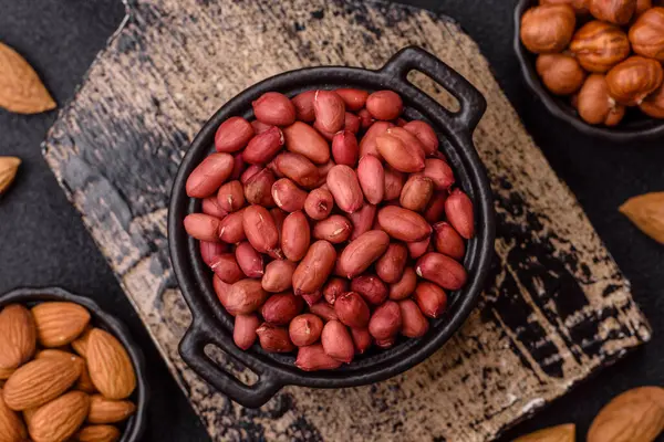 Koyu beton arka planda bir kasede yer fıstığı ya da kabuğu soyulmuş graundnut. Protein kaynağı olarak fındık