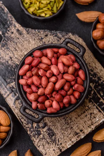 Koyu beton arka planda bir kasede yer fıstığı ya da kabuğu soyulmuş graundnut. Protein kaynağı olarak fındık