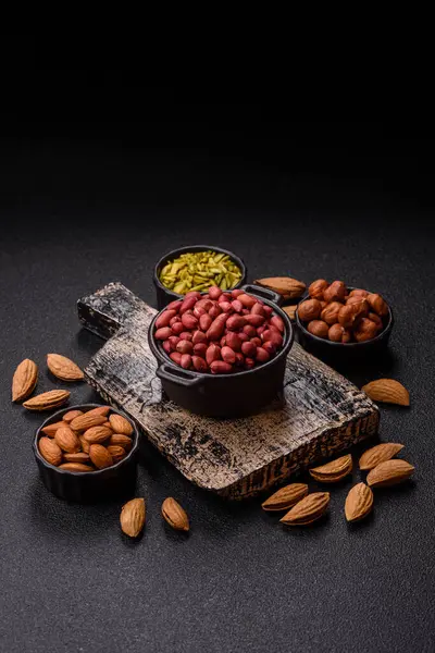 Koyu beton arka planda bir kasede yer fıstığı ya da kabuğu soyulmuş graundnut. Protein kaynağı olarak fındık