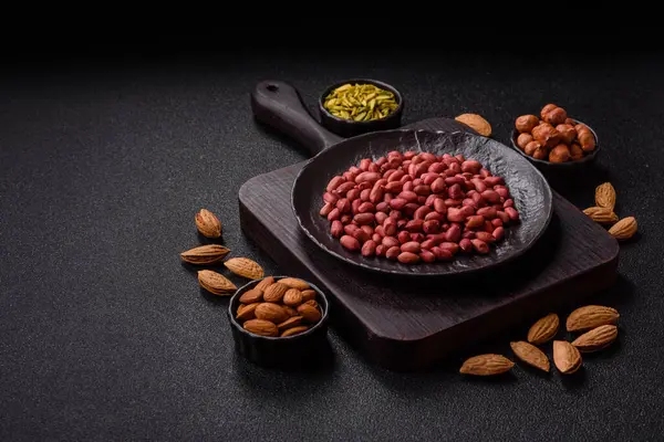 Koyu beton arka planda bir kasede yer fıstığı ya da kabuğu soyulmuş graundnut. Protein kaynağı olarak fındık