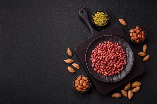 Koyu beton arka planda bir kasede yer fıstığı ya da kabuğu soyulmuş graundnut. Protein kaynağı olarak fındık