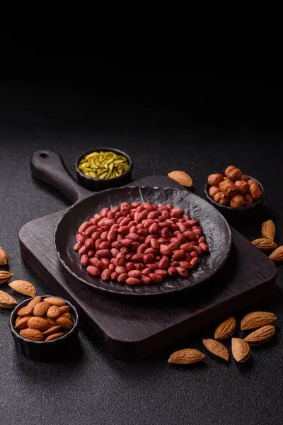 Koyu beton arka planda bir kasede yer fıstığı ya da kabuğu soyulmuş graundnut. Protein kaynağı olarak fındık