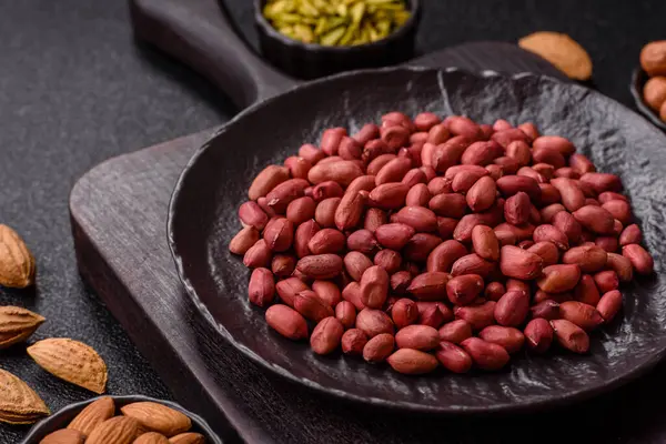 Koyu beton arka planda bir kasede yer fıstığı ya da kabuğu soyulmuş graundnut. Protein kaynağı olarak fındık