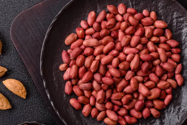 Koyu beton arka planda bir kasede yer fıstığı ya da kabuğu soyulmuş graundnut. Protein kaynağı olarak fındık