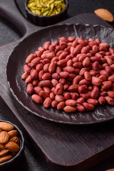 Koyu beton arka planda bir kasede yer fıstığı ya da kabuğu soyulmuş graundnut. Protein kaynağı olarak fındık