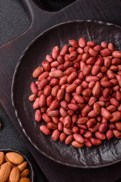 Koyu beton arka planda bir kasede yer fıstığı ya da kabuğu soyulmuş graundnut. Protein kaynağı olarak fındık