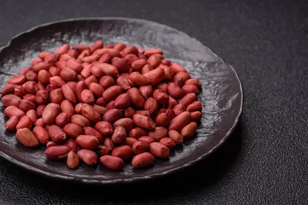 Koyu beton arka planda bir kasede yer fıstığı ya da kabuğu soyulmuş graundnut. Protein kaynağı olarak fındık