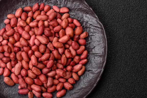 Koyu beton arka planda bir kasede yer fıstığı ya da kabuğu soyulmuş graundnut. Protein kaynağı olarak fındık