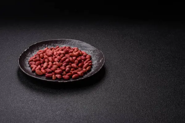 Koyu beton arka planda bir kasede yer fıstığı ya da kabuğu soyulmuş graundnut. Protein kaynağı olarak fındık