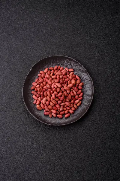 Koyu beton arka planda bir kasede yer fıstığı ya da kabuğu soyulmuş graundnut. Protein kaynağı olarak fındık
