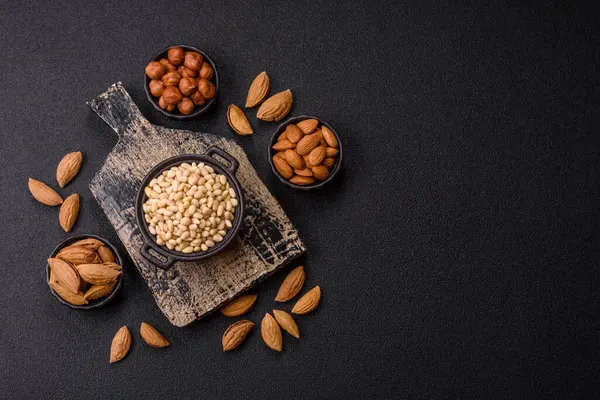 Koyu beton arka planda bir kasede soyulmuş çam fıstığı. Protein kaynağı olarak fındık.