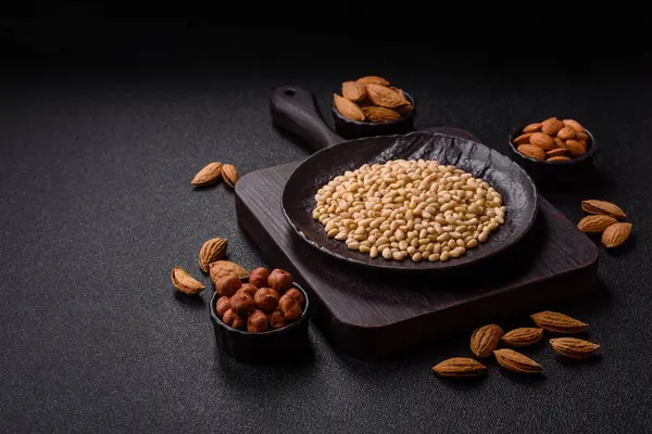 Koyu beton arka planda bir kasede soyulmuş çam fıstığı. Protein kaynağı olarak fındık.