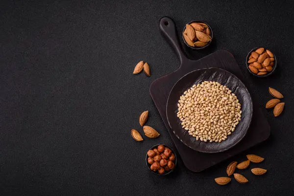 Koyu beton arka planda bir kasede soyulmuş çam fıstığı. Protein kaynağı olarak fındık.