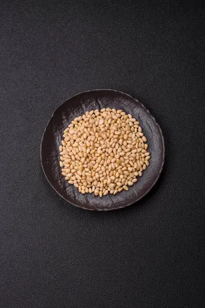 Koyu beton arka planda bir kasede soyulmuş çam fıstığı. Protein kaynağı olarak fındık.