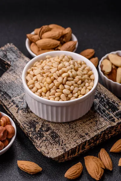 Koyu beton arka planda bir kasede soyulmuş çam fıstığı. Protein kaynağı olarak fındık.