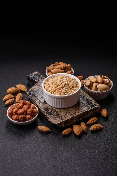 Koyu beton arka planda bir kasede soyulmuş çam fıstığı. Protein kaynağı olarak fındık.