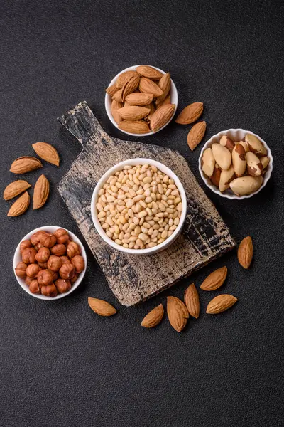 Koyu beton arka planda bir kasede soyulmuş çam fıstığı. Protein kaynağı olarak fındık.